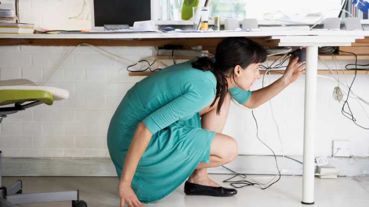 Women organizing cables under a desk